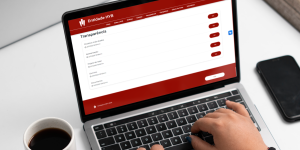 pessoa mexendo no computador em cima de uma mesa com uma página com documentos de transparência aberta